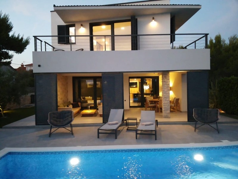 House front with terrace and illuminated pool