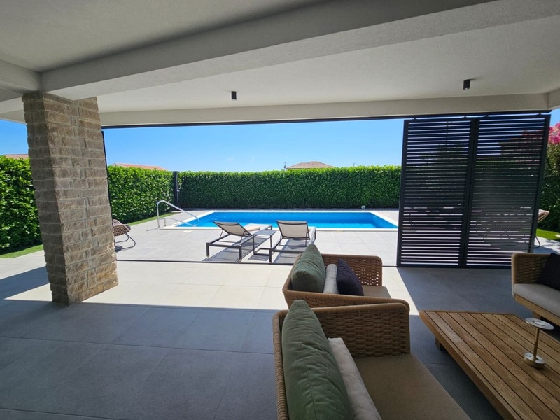Covered terrace with lounge furniture and views of the pool