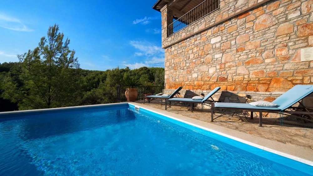 Swimming pool with sun loungers on the stone facade