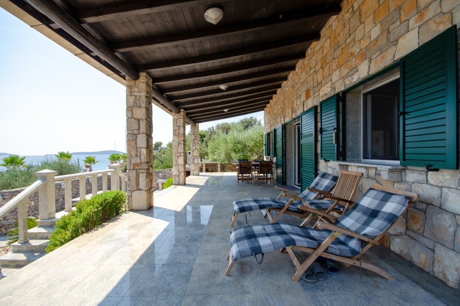 Covered terrace with loungers at the stone villa