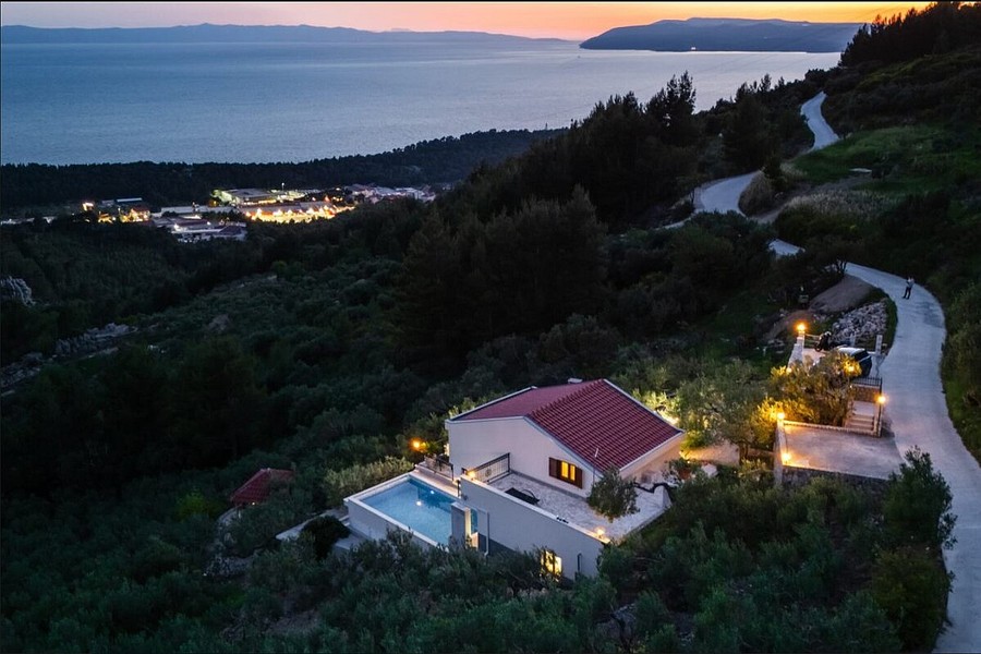 Hillside villa with illuminated pool in the evening