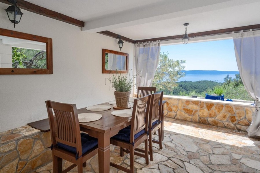 Covered dining area with stone wall and sea views