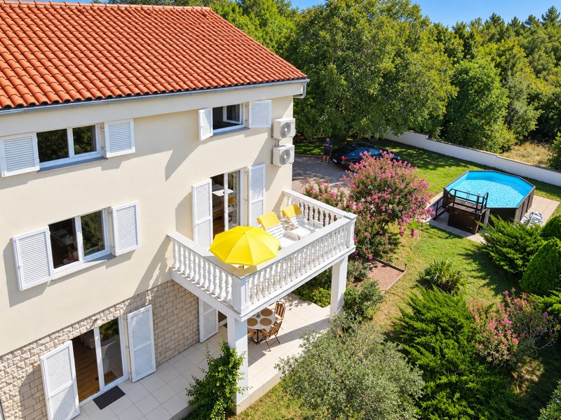 Balcony with loungers over the garden with pool