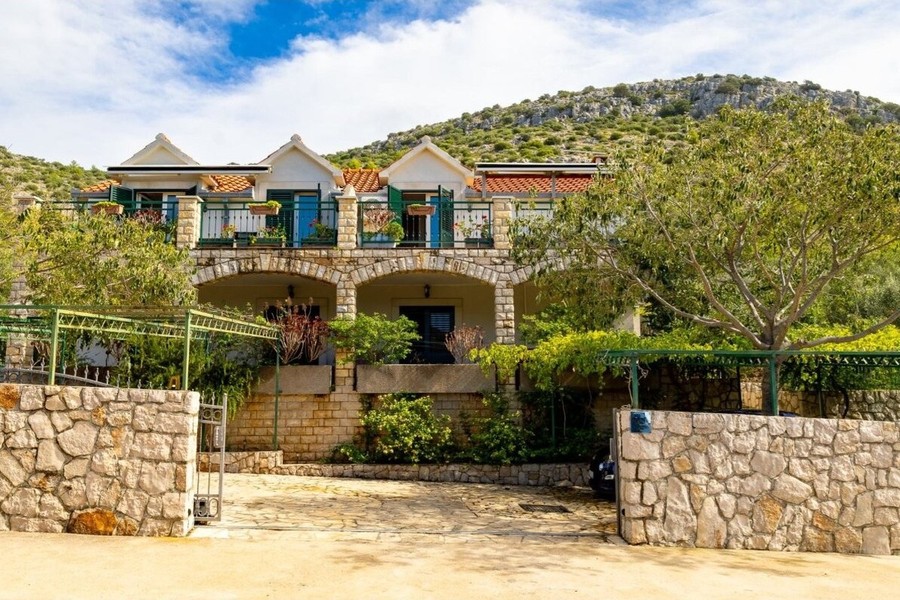 House exterior with natural stone wall and arcades on the ground floor