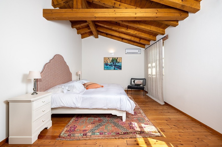 Bedroom with wooden beam ceiling, rug and air conditioning