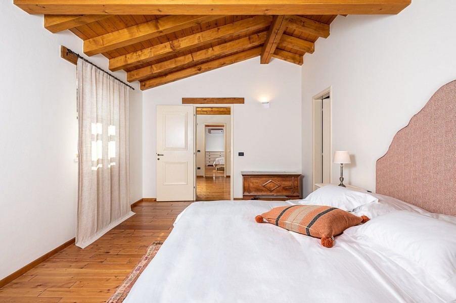 Double bed with orange cushion and open door