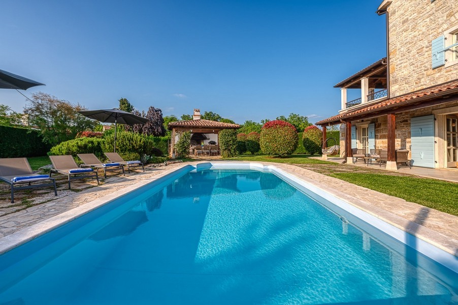 Poolside with sun loungers and pavilion in the background