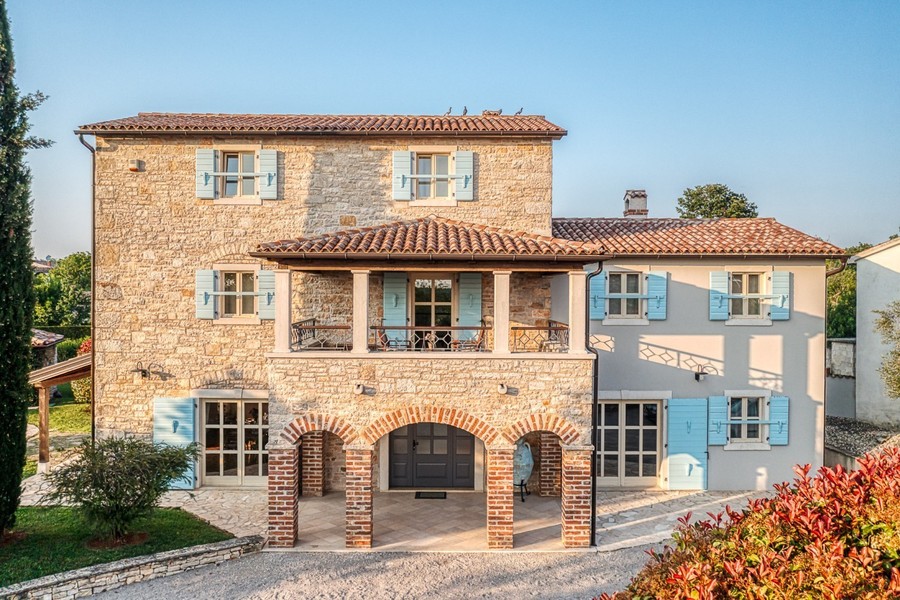 Natural stone house with round arches and light blue shutters