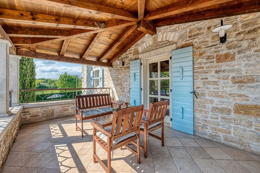 Covered balcony with wooden bench and wooden chairs