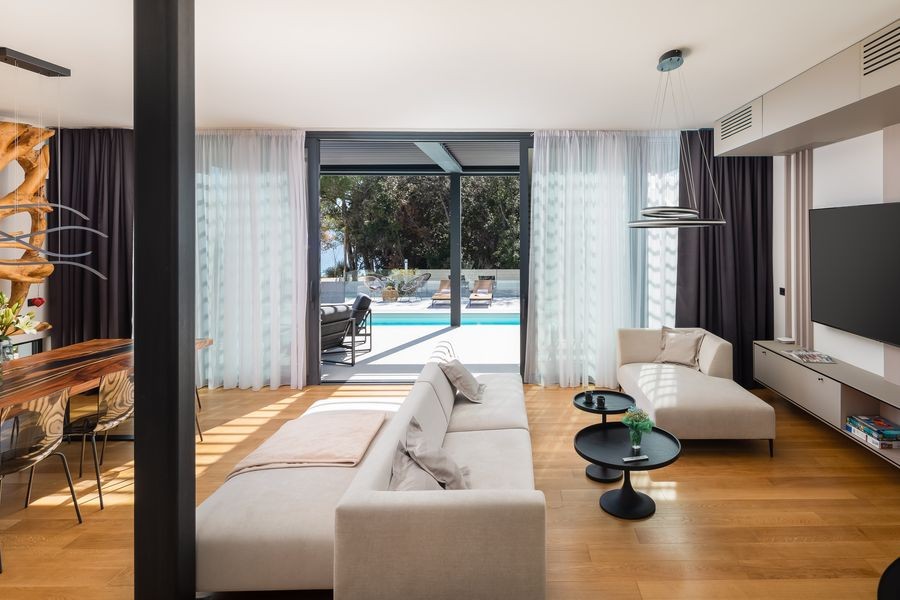 Living room with sofa and glass front facing the pool