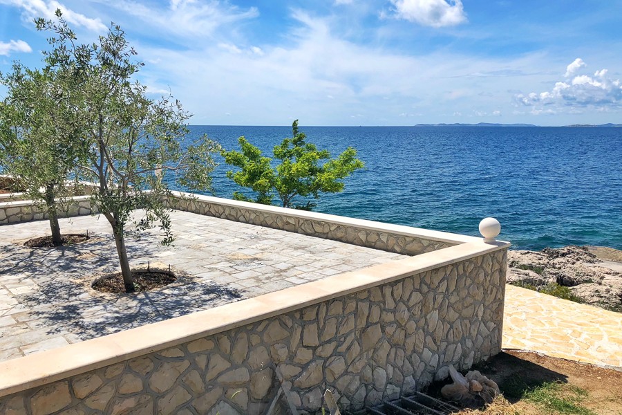 Stone terrace with olive trees by the sea