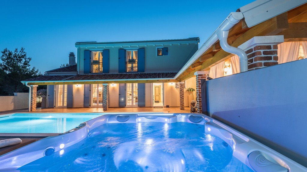 Illuminated pool and hot tub in the evening