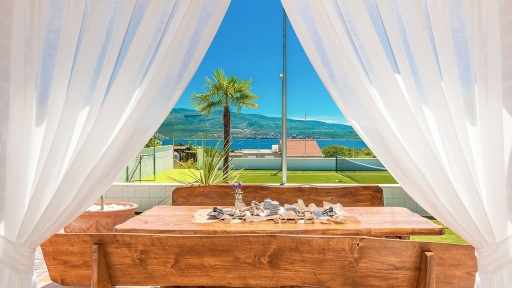 Covered terrace with wooden table and curtains