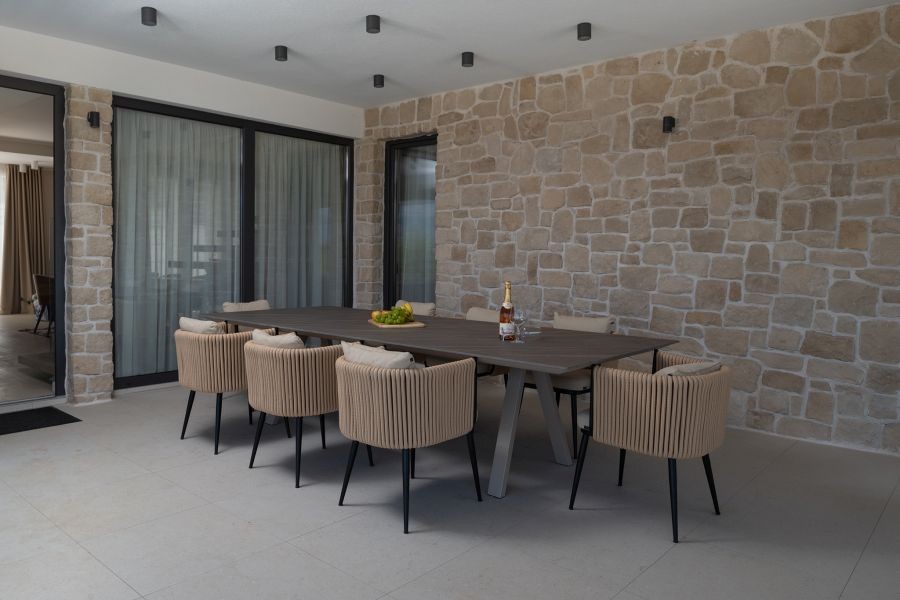 Covered terrace with dining table and natural stone wall