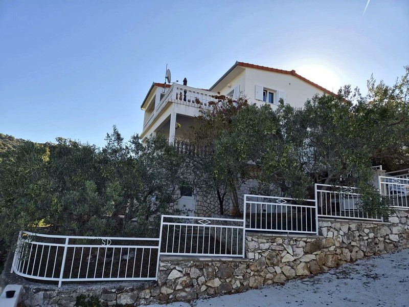 House on the slope with balconies and fence to the road