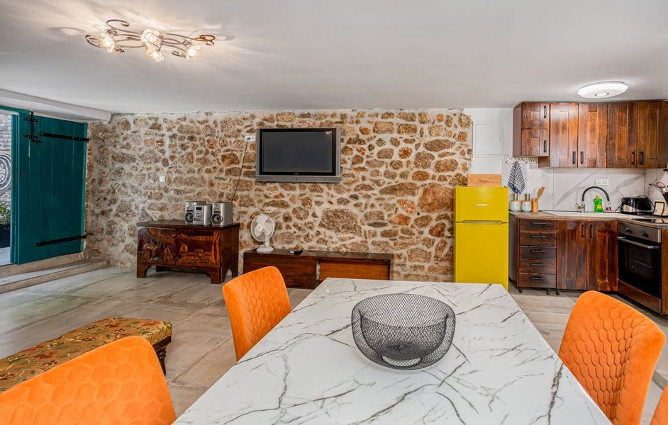 Dining table in front of natural stone wall with television