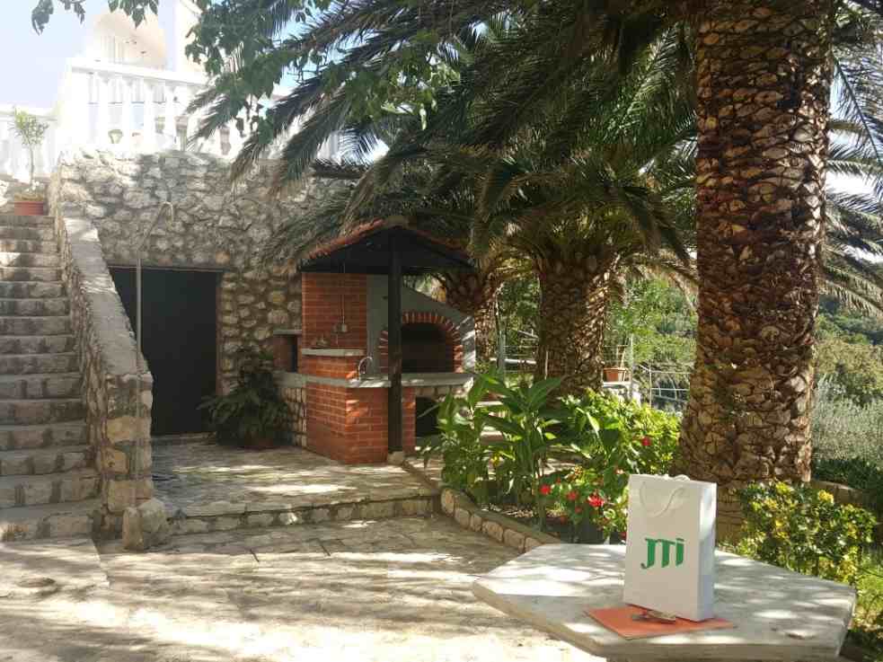 The courtyard of the apartment villa for sale on Pag is landscaped and planted in a Mediterranean style.