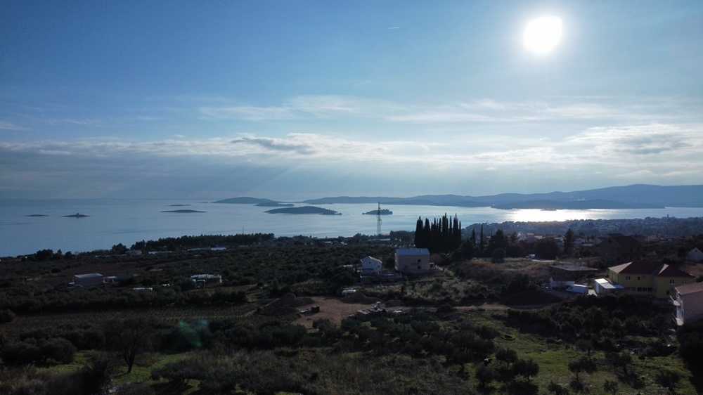 Aerial view of Orebic with a view of the coast, clear sky and the sea reflecting sunlight, with islands in the distance