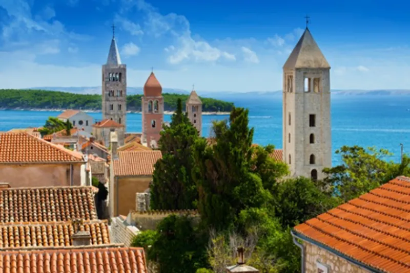 Old town of Rab with bell towers and a view of the sea